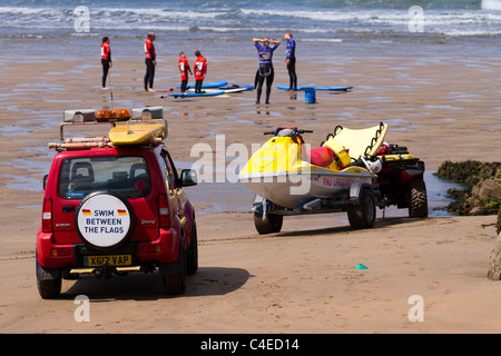 RNLI Royal National Lifeboat institution véhicule de patrouille de plage et jet ski   cours de surf sur la plage à Bude Bay, Devon, Royaume-Uni Banque D'Images