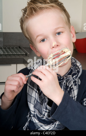 Boy eating la pâte qui est laissé derrière sur le batteur. Banque D'Images