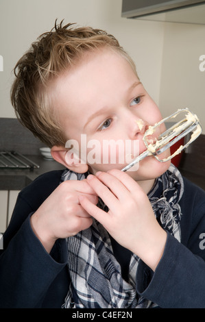 Boy eating la pâte qui est laissé derrière sur le batteur. Banque D'Images