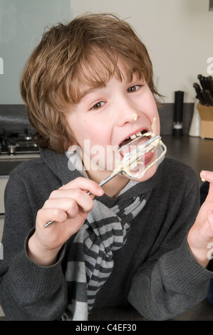 Boy eating la pâte qui est laissé derrière sur le batteur. Banque D'Images