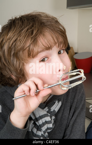 Boy eating la pâte qui est laissé derrière sur le batteur. Banque D'Images