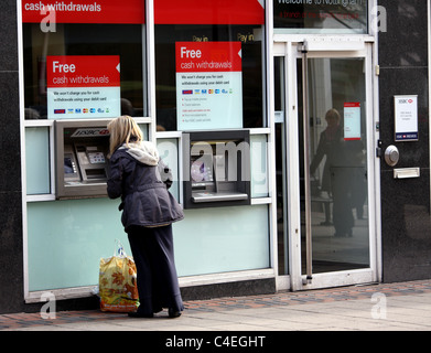 Une femme à l'aide d'une machine en argent de la HSBC auprès d'une banque locale pour vérifier son équilibre ou retirer de l'argent. Banque D'Images