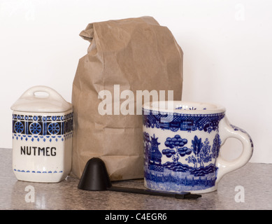 Ingrédients pour faire du café aromatisant à la muscade.Plats anciens en porcelaine bleue avec une cuillère à café et un sac de grains de café sur une étagère. Banque D'Images