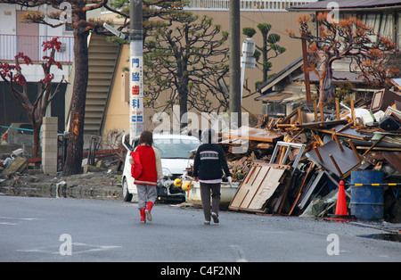 Les gens se promener dans une ville dévastée par le tsunami du 11 mars 2011 Ishinomaki Japon Miyagi Banque D'Images