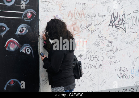 Une jeune fille écrit sur le mur de Berlin Banque D'Images