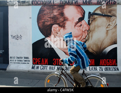 Un cycliste par la célèbre peinture murale de Honecker et Brejnev embrassant français sur le mur de Berlin à l'Eastside Gallery Berlin Banque D'Images