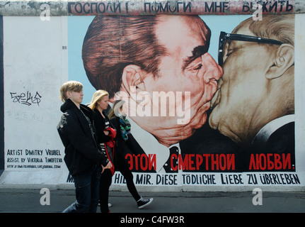 Les gens qui marchent par la célèbre peinture murale de Honecker et Brejnev embrassant français sur le mur de Berlin à l'Eastside Gallery Berlin Banque D'Images