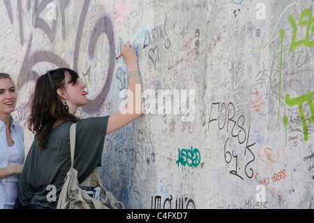Une jeune fille écrit sur le mur de Berlin Banque D'Images