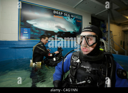 Divers kit-up avant d'entrer dans l'aquarium de Deep Sea World à plonger avec les requins tigre de sable qui sont les principales attractions Banque D'Images