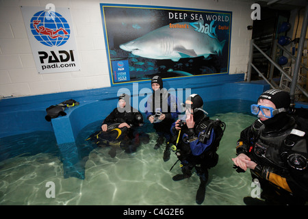 Divers kit-up avant d'entrer dans l'aquarium de Deep Sea World à plonger avec les requins tigre de sable qui sont les principales attractions Banque D'Images