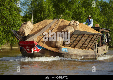 Un bateau rempli de balles de riz, Delta du Mékong, Vietnam Banque D'Images