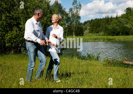 Bien qu'étant tout près de l'autre à un lac d'exécution sur l'herbe sur la rive Banque D'Images