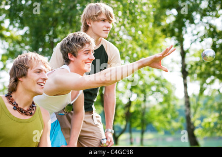 Groupe de jeunes hommes jouant aux boules à un lac à l'extérieur en été Banque D'Images