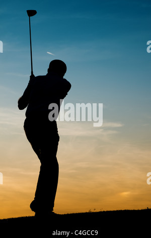 Senior golf - représenté comme une silhouette contre un ciel du soir Banque D'Images