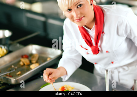 Femme chef dans un restaurant ou un hôtel cuisine cuisine délicieuse, elle termine la vaisselle Banque D'Images