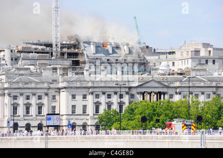 London fire brigade de pompiers sur place à la maison Marconi de l'immeuble en feu de toit site Strand skyline vu au-delà de Somerset House England UK Banque D'Images
