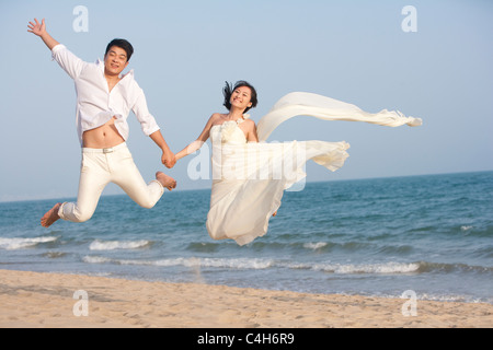 Heureux nouveaux mariés sauter de haut Banque D'Images