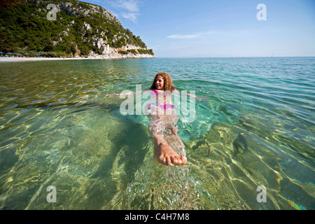 Jeune femme avec pink Bikini nager dans l'eau claire de la plage de Limnonari, île de Skopelos, Sporades du Nord, Grèce Banque D'Images