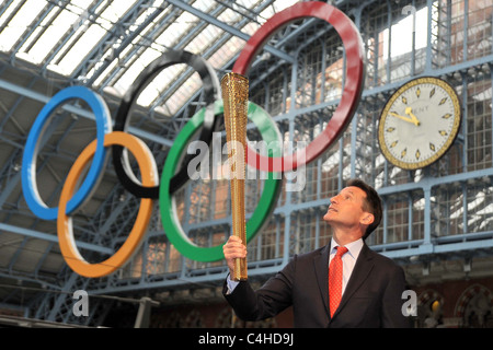 Sebastian Coe, président du LOCOG) regarde le flambeau qu'il tient sous les anneaux olympiques. La flamme olympique de Londres 2012 Banque D'Images