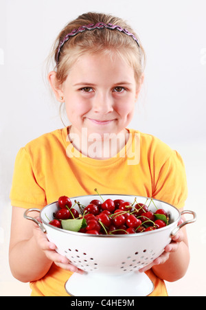 Mignon enfant tenant un bol de cerises fraîches Banque D'Images