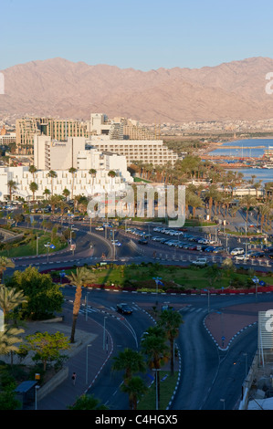 Une vue verticale de l'hôtel et la plage d'Eilat au coucher du soleil avec la ville et le littoral d'Aqaba en arrière-plan. Banque D'Images