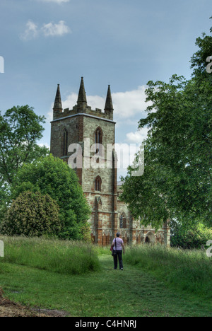 Une femme marche le long d'un chemin herbeux, vers l'église St Mary, Canons Ashby, UK Banque D'Images