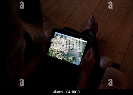 Homme assis dans le noir à regarder google earth sur son Ipad Banque D'Images