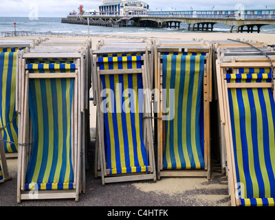 Des chaises longues en bois avec la jetée de l'arrière-plan Bournemouth UK Banque D'Images