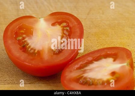 La tomate coupée en deux sur une planche en bois Banque D'Images