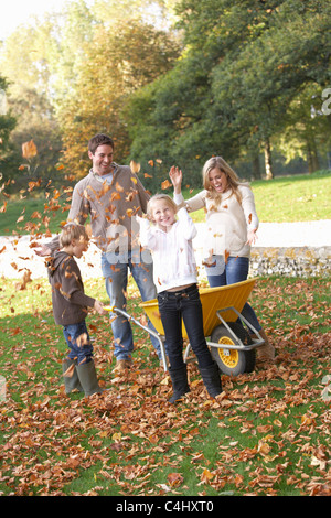 Jeter les feuilles d'automne de la famille en l'air dans le jardin Banque D'Images