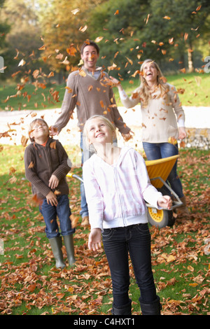 Jeter les feuilles d'automne de la famille en l'air dans le jardin Banque D'Images