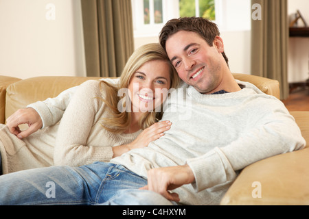 Jeune couple assis et relaxing on sofa Banque D'Images