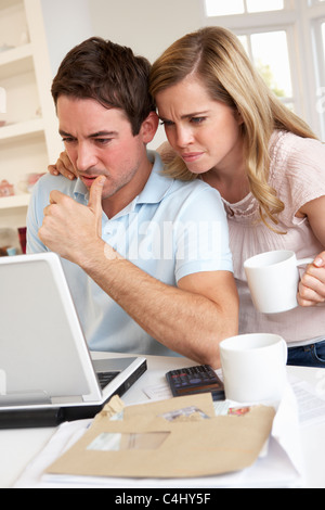 Jeune couple à la réflexion et à un ordinateur portable Banque D'Images