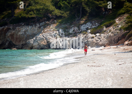 Seul homme à marcher le long de la plage de Gialos Milia vide sur l' île de Skopelos, Sporades du Nord, Grèce Banque D'Images
