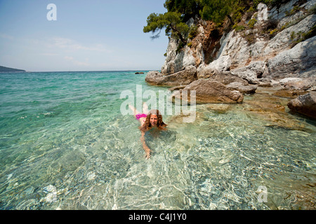 Jeune femme nageant dans l'eau claire de Gialos plage Kastani, Mamma Mia film emplacement sur l' île de Skopelos, Grèce Banque D'Images