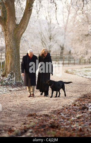 Senior Couple On Winter Walk avec chien au Frosty Landscape Banque D'Images