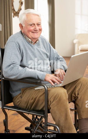 Mobilité Senior Man Sitting in Wheelchair Using Laptop Banque D'Images