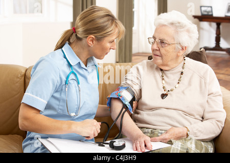 Senior Woman having Blood Pressure prises par Santé visiteur à l'accueil Banque D'Images