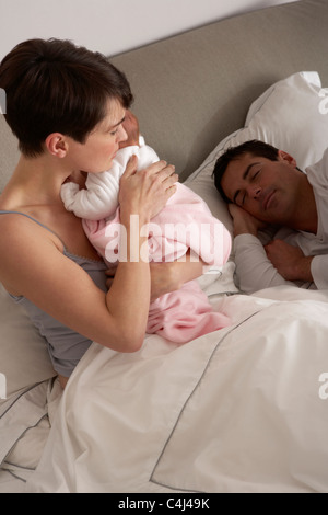 Mère de câliner bébé nouveau-né dans le lit à la maison Banque D'Images