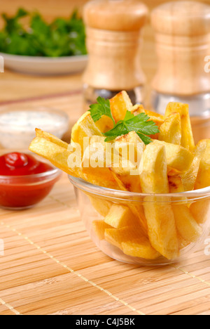 Les frites dans le bol en verre sur la table en bois Banque D'Images