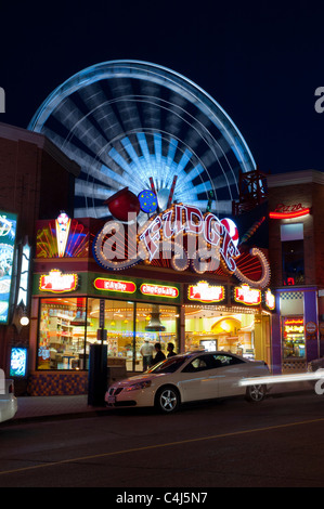 Les feux lumineux et colorés de Clifton Hill dans la nuit avec la grande roue en mouvement en arrière-plan. Banque D'Images