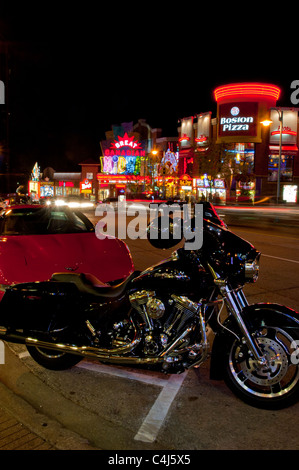 Une moto Harley-Davidson noir sur les vitrines éclairées de la rue Clifton Hill, Niagara Falls, Ontario, Canada. Banque D'Images