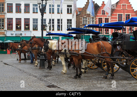 Une ligne de calèches touristes attend un jour de pluie à Bruges, Belgique. Banque D'Images