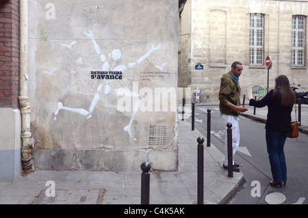 Un morceau de graffiti par Jérome Mesnager dans la rue du Pot de Fer, Paris France. À côté, un couple de converser. Banque D'Images