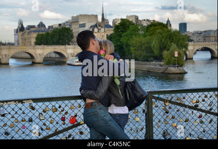 Un couple s'étreinte sur le Pont des Arts au-dessus de la Seine à Paris, France Banque D'Images