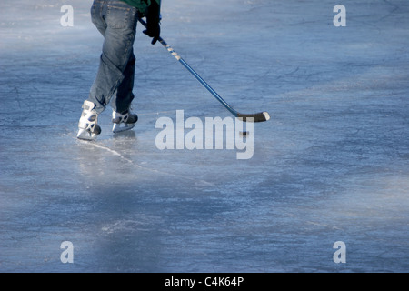 Evergreen, Colorado - un joueur de hockey patins sur la glace tout en essayant de manipuler la rondelle dans le but. Banque D'Images