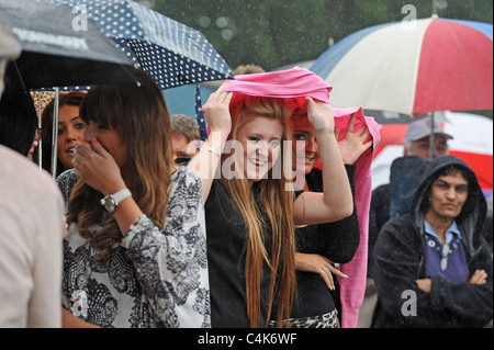 Foules d'essayer de mettre à l'abri de la pluie comme ils se regarder les troupes du Princess of Wales's Royal Regiment Banque D'Images