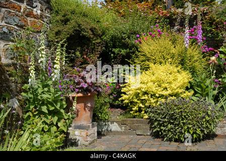 Un paysage coloré image d'un jardin typiquement anglais avec une variété de pots et fleurs contre un mur de brique de jardin. Banque D'Images