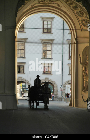 Silhouette de conducteur à cheval et un chariot roulant dans arch cours à Vienne Banque D'Images