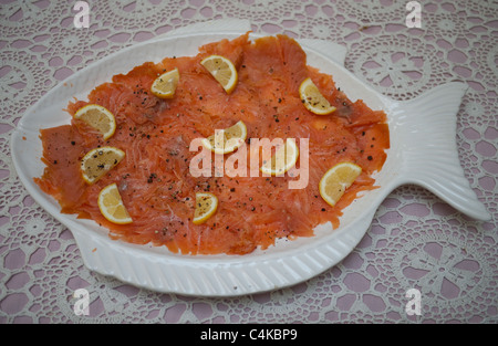 En forme de poisson blanc, assiette de saumon fumé au citron sur table avec tapis de table Banque D'Images